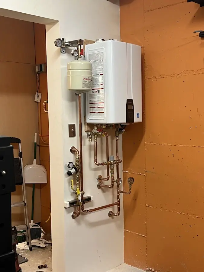Plumbing technician inspecting water heater connections in Enfield